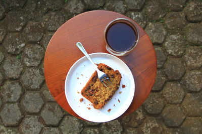 A slice of banana bread on white plate and a cup of  coffee for breakfast on table