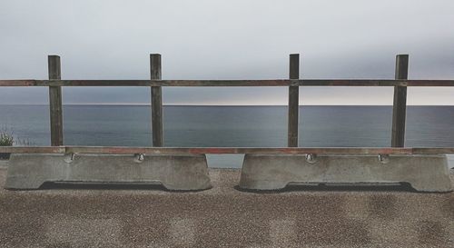 Railing by sea against clear sky