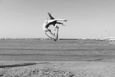 Upside down image of man jumping over sea against clear sky