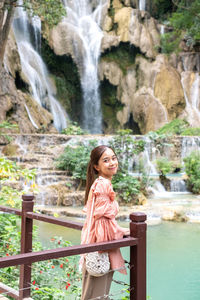 Young woman standing against waterfall