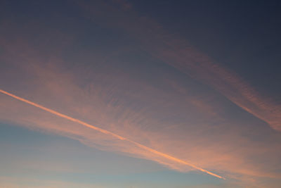 Low angle view of vapor trails in sky during sunset