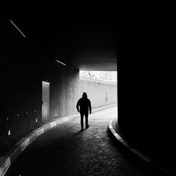 Rear view of man walking in tunnel