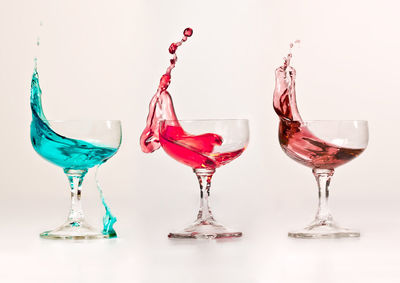 Drink splashing in glasses over white background