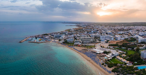 High angle view of townscape by sea against sky during sunset