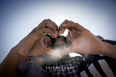 Close-up of hands against sky