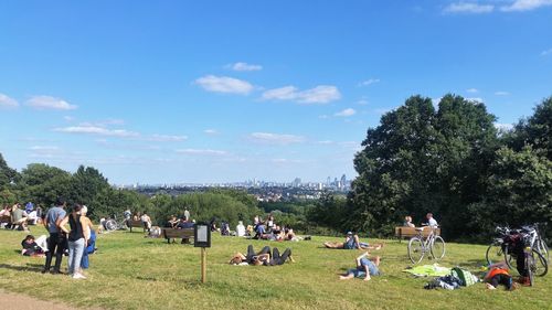 People on lawn in park against sky