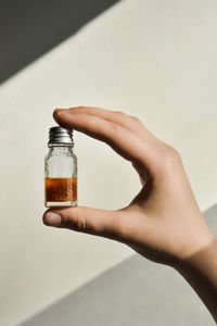 Cropped hand of woman holding bottle on table