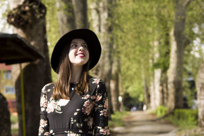 Portrait of young woman standing against trees