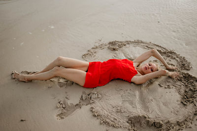 Low section of woman relaxing on sand at beach