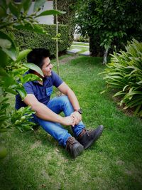 Smiling boy sitting on grass against trees