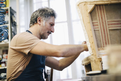 Mature craftsperson making furniture in workshop