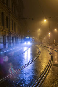 Illuminated street amidst buildings in city at night