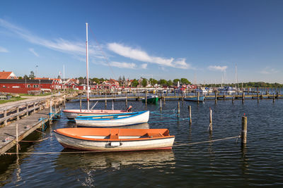 Boats moored in harbor against sky