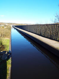 Narrow canal against clear blue sky