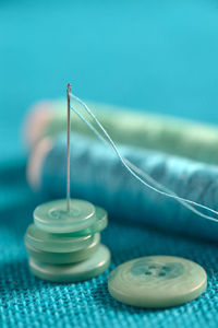 Close-up of buttons and thread with sewing needle on table