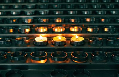 Three burning candles in between many candles at church