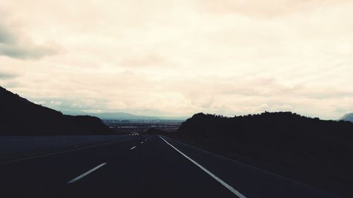 Empty road along landscape against sky