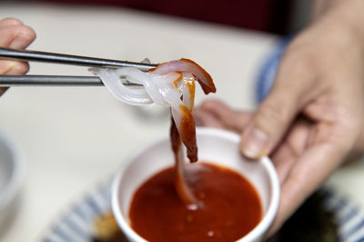 Cropped hand of person holding squid sashimi 