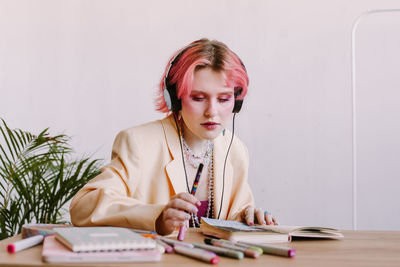 Creative young woman using smartphone , listen to music at table with scetchbook 