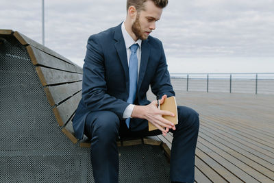 Full length of young man sitting on seat