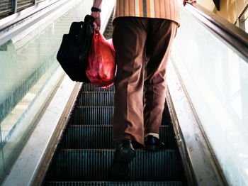 Low section of man standing on escalator at railroad station