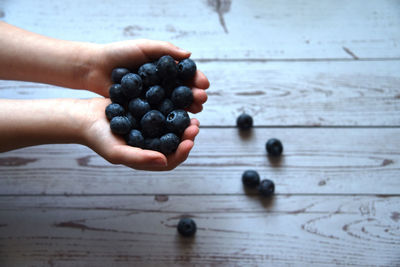 Cropped image of hand holding fruits on table