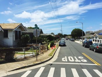 Cars parked on street by houses against sky