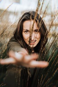 Portrait of smiling young woman gesturing amidst plants