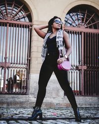 Full length portrait of young woman standing against built structure