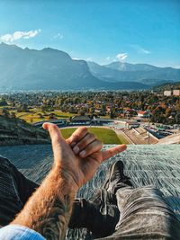 Low section of man gesturing against landscape and sky