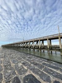 Bridge over sea against cloudy sky