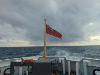 Red flag on sea against sky