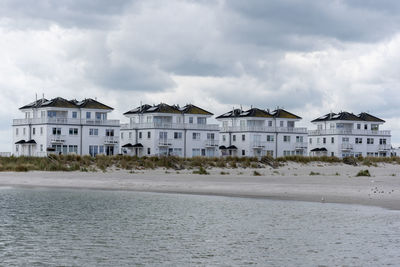 Houses on beach by buildings against sky