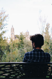 Rear view of woman sitting on railing