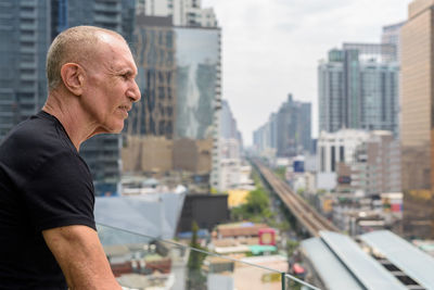 Side view of man looking at city buildings