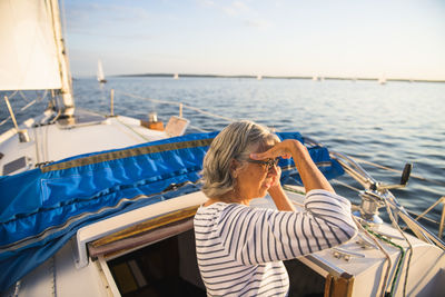 Rear view of woman on sailboat in sea against sky