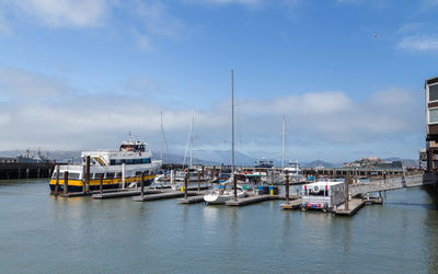 Sailboats moored at harbor against sky