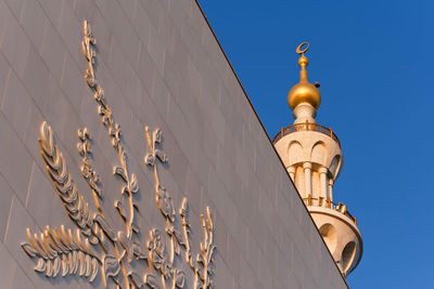 Low angle view of cross amidst buildings against sky