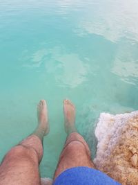 Low section of person relaxing in swimming pool