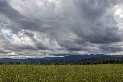 Scenic view of field against storm clouds