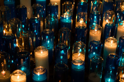 Illuminated burning tea lights at church in dark