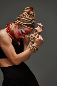 Side view of woman with arms crossed standing against black background