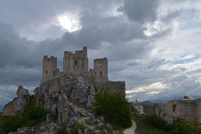 Low angle view of ruined rocca calascio against cloudy sky