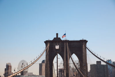 American flag on brooklyn bridge against clear sky in city