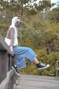 Side view of young man wearing sunglasses against trees