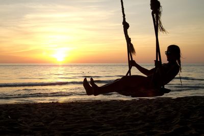 Silhouette man on beach against sky during sunset