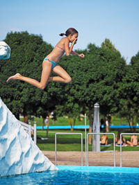 People jumping in swimming pool against sky