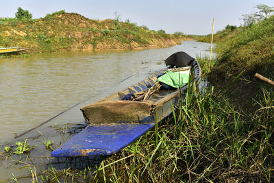 Boat moored on shore by lake against sky