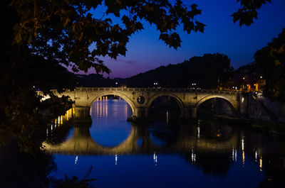 Bridge over river against sky at night