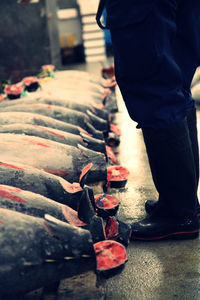 Low section of man standing by tuna fish for sale at market